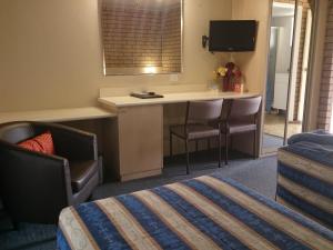 a hotel room with a desk and a bed at Fountain View Motel in Dubbo