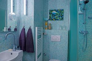 ein blau gefliestes Bad mit einer Dusche und einem Waschbecken in der Unterkunft Ankerplatz 57 in Neustadt in Holstein