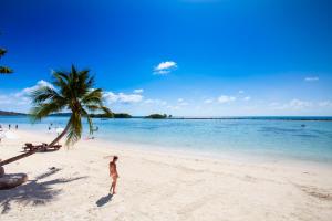 a man standing on a beach with a palm tree at The Stay Chaweng Beach Resort- SHA Plus in Chaweng