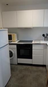 a white kitchen with a stove and a microwave at les tilleuls in Léon +3 photos