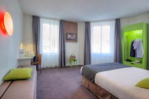 a bedroom with a bed and a desk and windows at Campanile Annecy Centre - Gare in Annecy