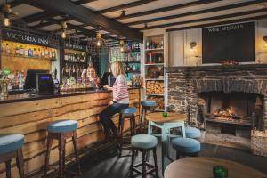 a woman standing at a bar with a fireplace at Victoria Inn in Salcombe