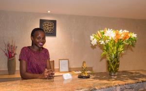 a woman standing at a counter with a vase of flowers at Nyali Beach Holiday Resort in Nyali