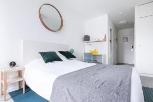 a white bedroom with a large bed and a mirror at Student Factory Paris Bagnolet in Bagnolet