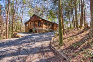 a log cabin in the woods with a road leading to it at Puppy Love #1619 in Gatlinburg