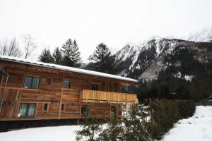 una cabaña de madera en la nieve con montañas en el fondo en Chalet des Amis appt 1 - Chamonix All Year, en Chamonix-Mont-Blanc
