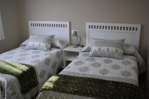 1 dormitorio con 2 camas y mesa con lámpara en CASA AMABLE en La Roza