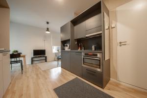 a kitchen with stainless steel appliances and a living room at Spot Apartments Hiekkaharju in Vantaa