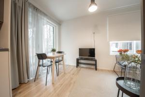 a living room with a table and a television at Spot Apartments Hiekkaharju in Vantaa