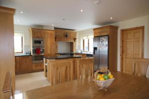 una cocina con armarios de madera y una mesa con un bol de fruta en King's Lodge en Cleggan