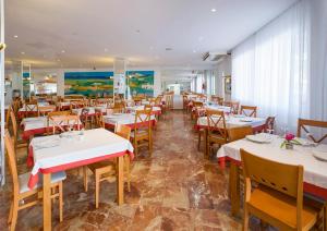 un restaurant avec des tables blanches et des chaises en bois dans l'établissement Coral Star Apartments, à Bahía de Sant Antoni