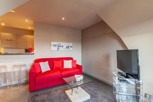 een woonkamer met een rode bank en een tv bij CMG Place Morny/ Deauville in Deauville