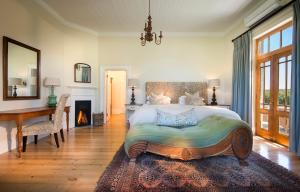 1 dormitorio con cama, escritorio y chimenea en Kwandwe Uplands Homestead, en Grahamstown