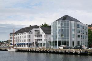 ein großes Gebäude neben einem Wasserkörper in der Unterkunft Clarion Hotel Tyholmen in Arendal