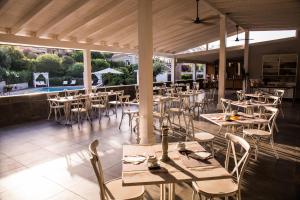 a restaurant with tables and chairs and a pool at Albaruja Hotel in Costa Rei