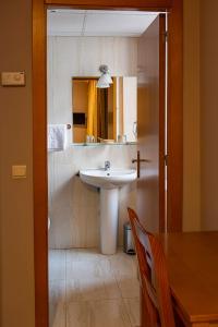 baño con lavabo, mesa y espejo en Hotel Castilla, en Cáceres