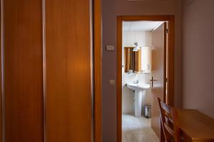 Baño con puerta que da a un baño con lavabo en Hotel Castilla, en Cáceres