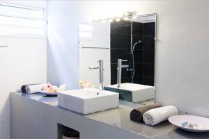 un bagno con un lavandino bianco e uno specchio di Turquoise a Le Diamant