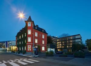 a red building with a tower on a street at Hotel Schwärzler in Bregenz