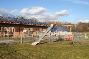 een speeltuin met een glijbaan voor een gebouw bij Pferdefreunde Loberhof in Weihenzell