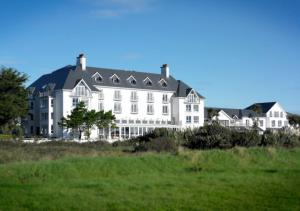 
a white house with a blue roof and some trees at Garryvoe Hotel in Ballycotton
