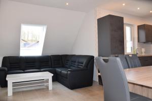 uma sala de estar com um sofá preto e uma mesa em Pferdefreunde Loberhof em Weihenzell