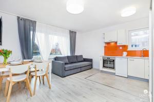 a kitchen and living room with a table and a couch at Jantar Apartamenty - Willa Jałowcowa in Grzybowo