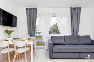 a living room with a couch and a table at Jantar Apartamenty - Willa Jałowcowa in Grzybowo