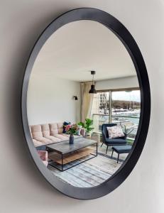 a mirror reflecting a living room with a couch and a table at Marina View One Bedroom Dream Suite in Herzelia 