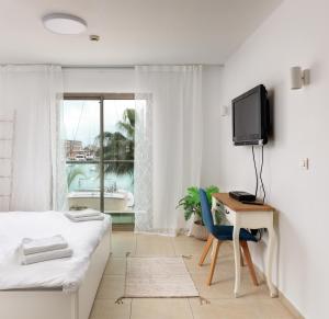 a bedroom with a bed and a desk and a tv at Marina View One Bedroom Dream Suite in Herzelia 