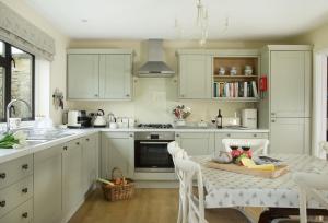 uma cozinha com armários brancos e uma mesa com comida em Fairfields em Moreton-in-Marsh