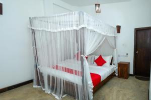 a bedroom with a white canopy bed with red pillows at French Garden Kandy in Kandy