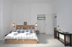 a white bedroom with a bed and a desk and a door at Guest House La Genesa in Cernobbio