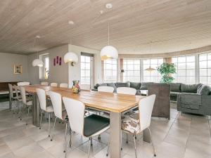 a dining room with a large wooden table and white chairs at 16 person holiday home in Hvide Sande in Hvide Sande