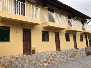ein gelbes Gebäude mit Balkonen und einer Steinmauer in der Unterkunft Village Funchal 01 in Lençóis