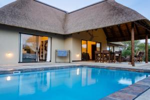 a villa with a swimming pool and a thatch roof at Hidden 2-Bedroom Gem In A Quiet Wildlife Estate in Hoedspruit