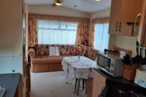 - un salon avec un canapé et une table fleurie dans l'établissement Kimberley Lane Static, Cornwall, à Gwennap