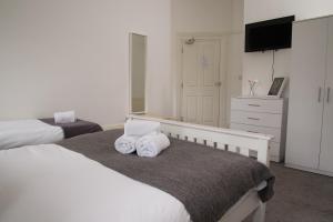 a bedroom with two beds and a flat screen tv at TLK Apartments & Hotel - Beckenham Junction in London