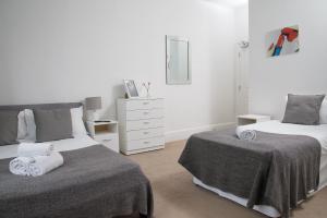 a white bedroom with two beds and a dresser at TLK Apartments & Hotel - Beckenham Junction in London