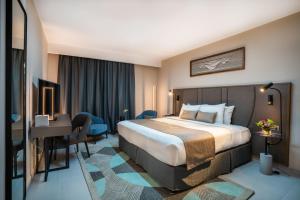 a hotel room with a bed and a desk at Hotel Holiday International in Sharjah