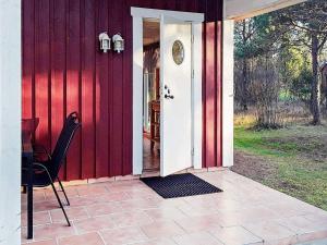 een open deur naar een rood huis met een stoel bij 4 person holiday home in M nster s in Mönsterås