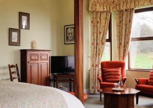 a bedroom with a bed and a tv and a chair at Lough Inagh Lodge Hotel in Recess