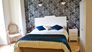 a bedroom with a bed with blue pillows on it at L'Hôtel du Périgord in Aubeterre-sur-Dronne
