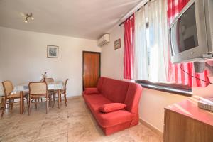 a living room with a red couch and a table at Apartment Villa Mare1 with pool, sea view and hydromassage in Banjole