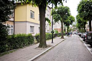 a sidewalk with trees and a building and cars at White Sand Apartment Centrum by Grand Apartments in Sopot