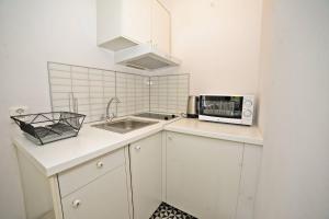 a white kitchen with a sink and a microwave at White Rock Apartment by Grand Apartments in Sopot