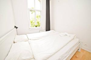 a white bed in a white room with a window at White Rock Apartment by Grand Apartments in Sopot