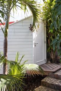 uma garagem branca com uma porta e uma palmeira em Franca St Jean em Saint-Jean