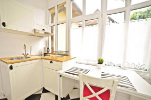 a kitchen with white cabinets and a table with a chair at White Marina Apartment by Grand Apartments in Sopot