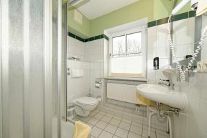 a bathroom with a sink and a toilet and a window at Hotel zum Maximilian in Bad Feilnbach